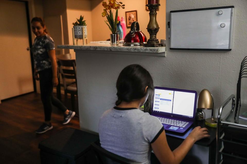 Jaqueline Avina, 15, checks her homework for the week from her school at home in Austin, Texas, in May as her mother, Alma Vargas, does chores.