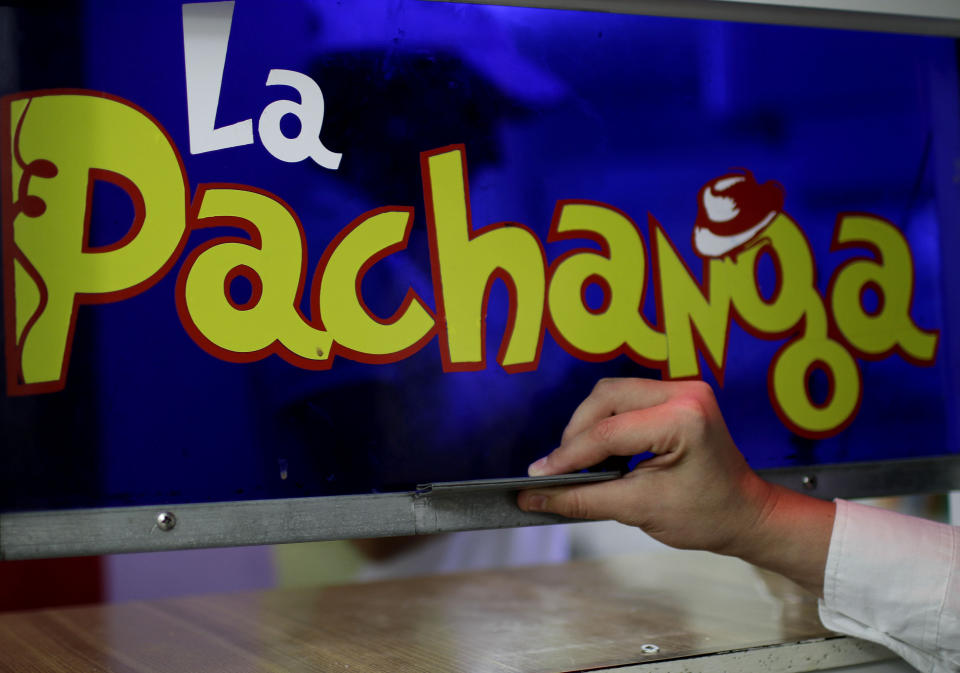 In this June 9, 2012 photo, employee Claudia Montano opens a logo-covered window to the kitchen at the private cafeteria "La Pachanga" in Havana. For decades, Communist-run Cuba has essentially been free of commercial advertising. But it's a knotty problem for thousands of budding entrepreneurs who have embraced President Raul Castro's push for limited free-market reform. So they're turning to guerrilla marketing. (AP Photo/Franklin Reyes)