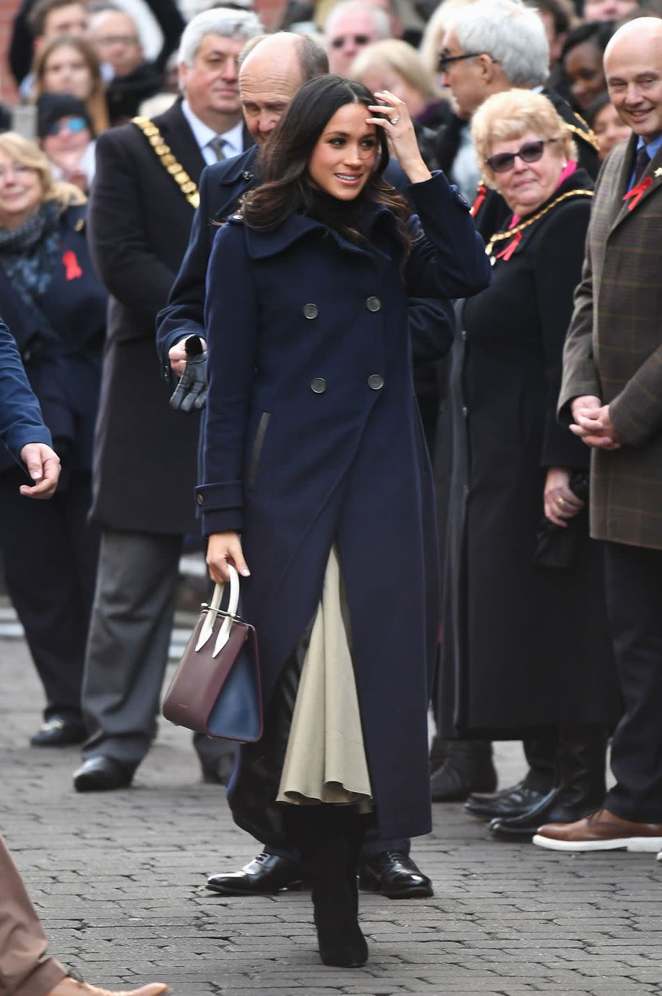 <p>Meghan looked her usual classy self for her first official royal engagement with Prince Harry. Wearing a navy double breasted wool coat from Canadian brand Mackage and a <a href="https://www.strathberry.com/products/the-strathberry-midi-tote-tri-colour-burgundy-navy-vanilla" rel="nofollow noopener" target="_blank" data-ylk="slk:Strathberry Midi-Tote;elm:context_link;itc:0;sec:content-canvas" class="link ">Strathberry Midi-Tote</a> handbag, both of which sold out instantly obvs. </p>