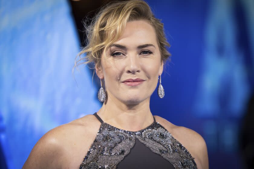 A woman with blond hair in an updo wearing a gray sparkly dress