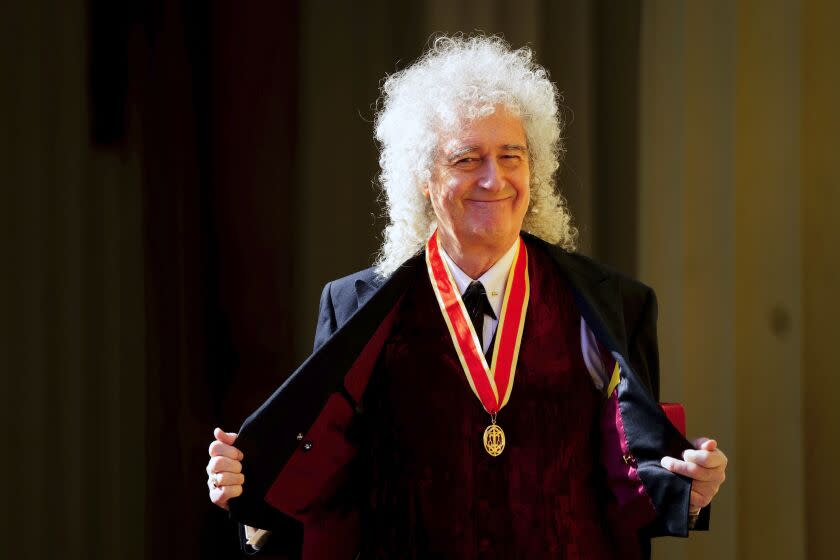 A man wearing a red medallion around his neck holds open his jacket