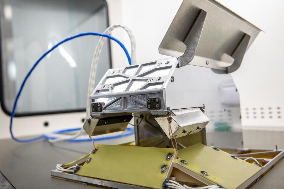 a metal box with wires protruding from it sits on a workbench in a white laboratory