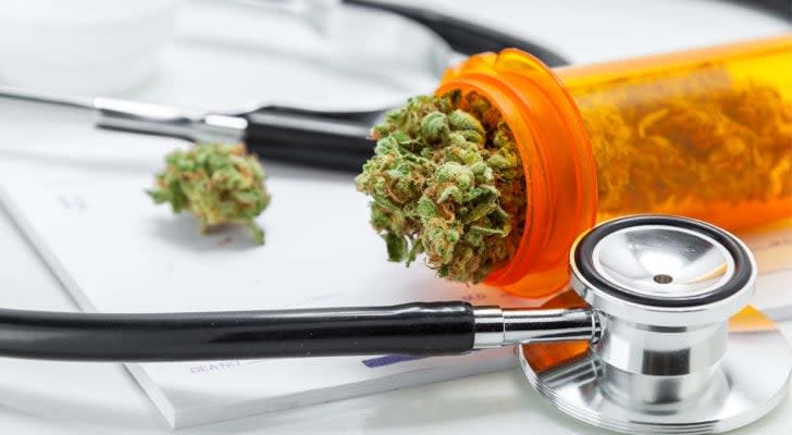 marijuana falling out of a prescription container next to a stethoscope