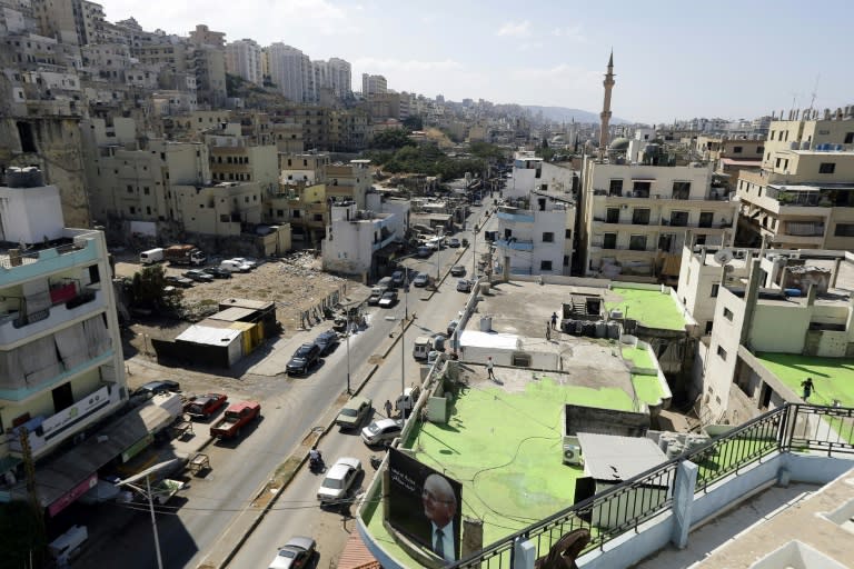 Lebanese painters work on September 28, 2017 as part of a project to write the word Peace in Arabic across 85 rooftops joining rival Sunni and Alawite neighbourhoods of Tripoli