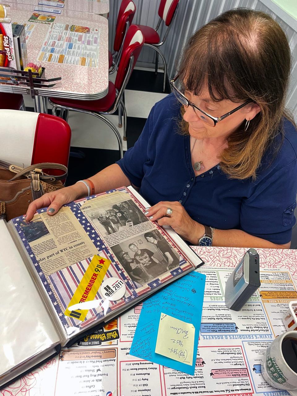 Nellie Garone, the high school teacher who coordinated the students' efforts to bring a 9/11 artifact to Milburn High School as their 2011 Class Legacy Project, looks over a scrapbook that documents their efforts.