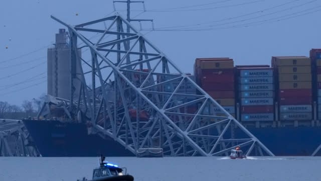 Portions of the collapsed Francis Scott Key bridge rest against a shipping vessel