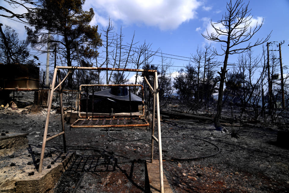 A burnt swing and burnt trees in a garden from a house during a wildfire in Thea area some 60 kilometers (37 miles) northwest of Athens, Greece, Thursday, Aug. 19, 2021. A major wildfire northwest of the Greek capital devoured large tracts of pine forest for a third day and threatened a large village as hundreds of firefighters, assisted by water-dropping planes and helicopters, battled the flames Wednesday. (AP Photo/Thanassis Stavrakis)