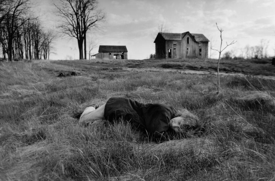 “My wife Ann and I had been digging during the day, transplanting lilies from the front of this abandoned farmhouse back down the road to where we live. We finished. She was tired and laid in the grass. I took a picture. The house is now gone. The walnut trees have been bulldozed and burned. I saw this picture the other day for the first time in years and realized how photographing life within a hundred yards of my front porch had helped me focus on everything I cared about.” -- Larry Towell (Ontario, 1997)