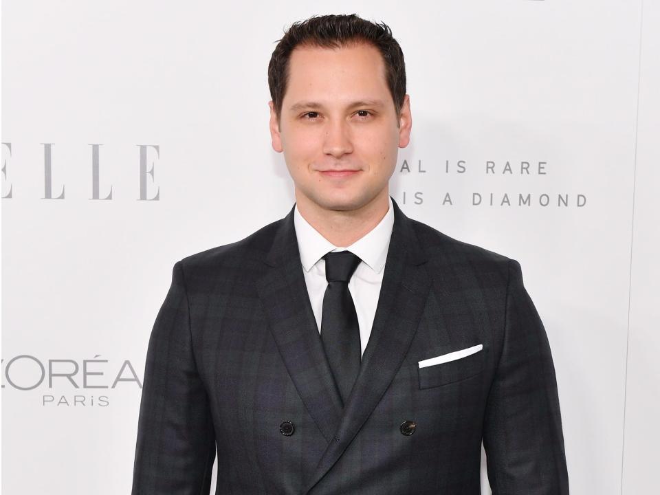 Matt McGorry smiling while wearing a black suit and tie.