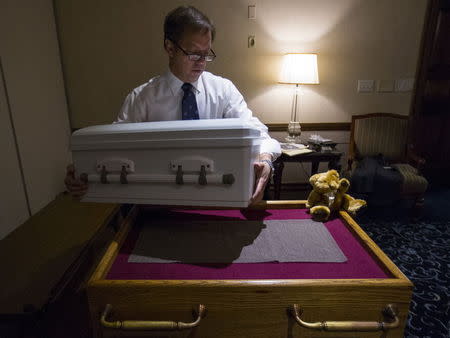 Glueckert Funeral Home Funeral Director John Glueckert lifts the casket containing the remains of an abandoned newborn baby on to a table in preparation for funeral and burial services in Arlington Heights, Illinois, June 19, 2015. REUTERS/Jim Young