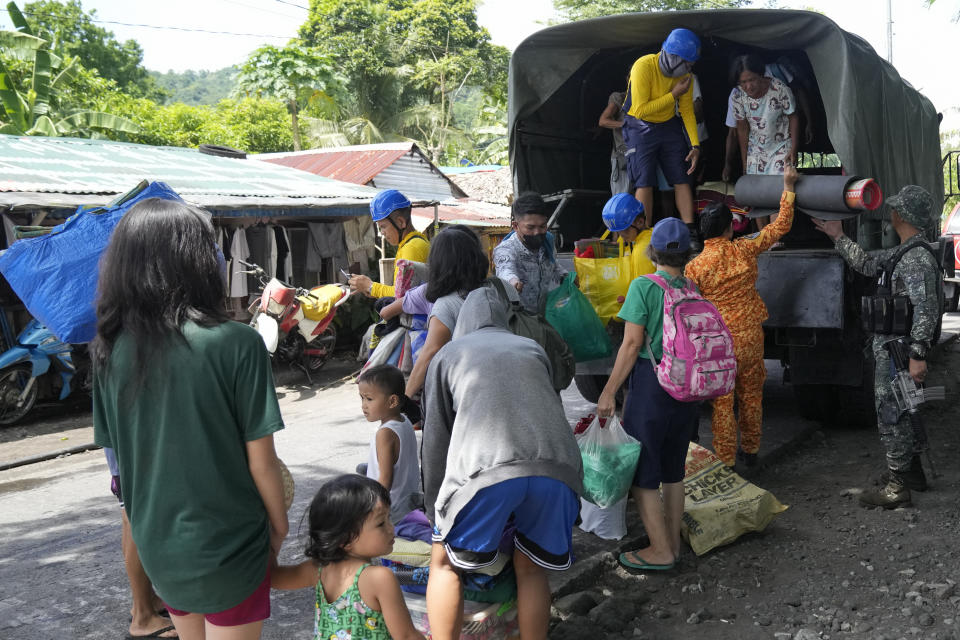 Residents are assisted as they come down from a military truck at an evacuation center in Santo Domingo town, Albay province, northeastern Philippines, Tuesday, June 13, 2023. Truckloads of villagers on Tuesday fled from Philippine communities close to gently erupting Mayon volcano, traumatized by the sight of red-hot lava flowing down its crater and sporadic blasts of ash. (AP Photo/Aaron Favila)