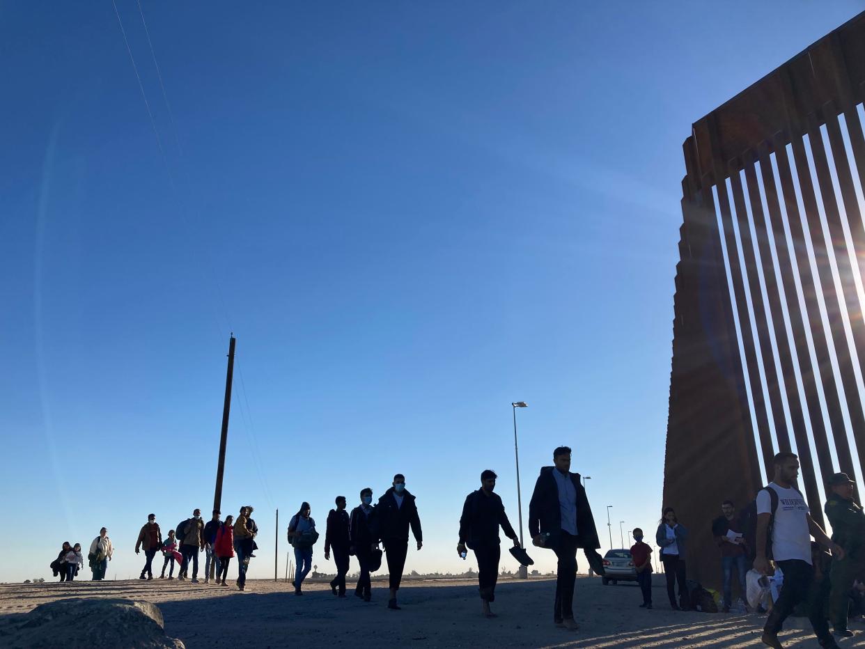 A group of migrants walk to line up in front of Border Patrol agents after crossing the U.S.-Mexico border illegally through the Yuma Sector near Somerton, Arizona, on Monday, Nov. 29, 2021.