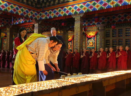 Catherine, Duchess of Cambridge, lights an oil lamp as Britain's Prince William, Duke of Cambridge, Bhutan's King Jigme Khesar Namgyel Wangchuck and his wife Jetsun Pema (L) look on at the Tashichho Dzong in Thimphu, Bhutan, in this April 14, 2016 handout photo by the Bhutanese Royal Office. REUTERS/Bhutanese Royal Office/Handout via Reuters