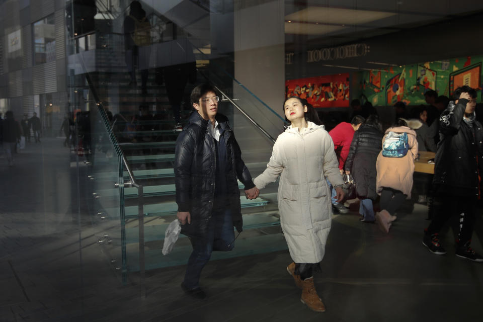 A couple with their purchased goods walks down staircase as they prepares to leave an Apple Store, at the capital city's popular shopping mall in Beijing, Wednesday, Feb. 13, 2019. U.S. and Chinese negotiators are meeting this week for their final trade talks before President Donald Trump decides whether to escalate a dispute over technology with a March 2 tariff hike on $200 billion of imports from China. (AP Photo/Andy Wong)