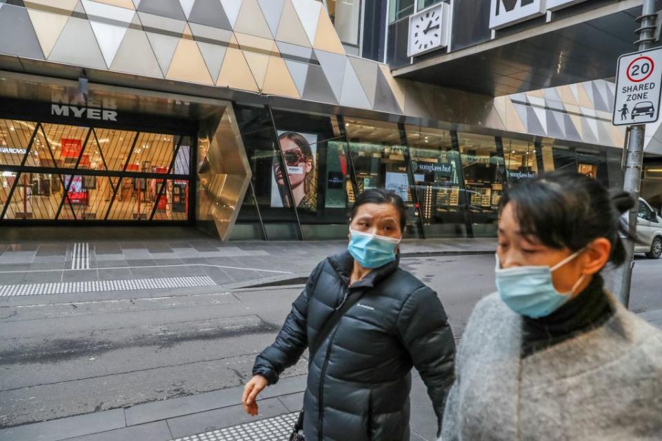 Pedestrians wearing face masks walk past a closed major department store in the Melbourne's Central Business District.