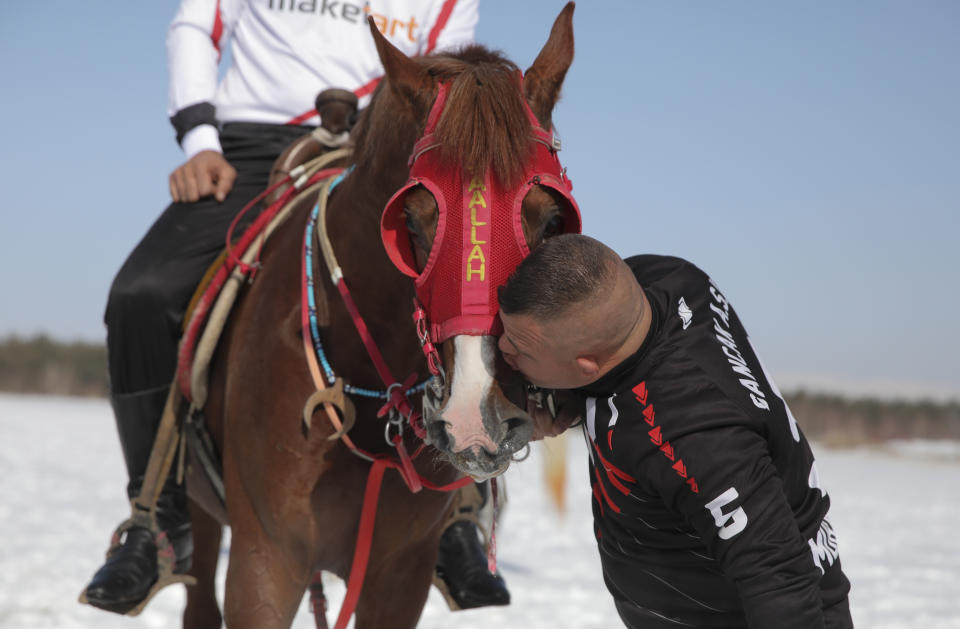 Selcuk Davulcu, 31, a horse groom for the Dadas (Comrades) local sporting club, cuddles a horse prior to a game of Cirit, a traditional Turkish equestrian sport that dates back to the martial horsemen who spearheaded the historical conquests of central Asia's Turkic tribes, between the Comrades and the Experts local sporting clubs, in Erzurum, eastern Turkey, Friday, March 5, 2021. The club officials said that Davulcu, a man with Down syndrome has been communicating with people just for the last four years thanks to the horses as they played a big role on his rehabilitation.The game that was developed more than a 1,000 years ago, revolves around a rider trying to spear his or her opponent with a "javelin" - these days, a rubber-tipped, 100 centimeter (40 inch) length of wood. A rider from each opposing team, which can number up to a dozen players, face each other, alternately acting as the thrower and the rider being chased. Cirit was popular within the Ottoman empire, before it was banned as in the early 19th century. (AP Photo/Kenan Asyali)