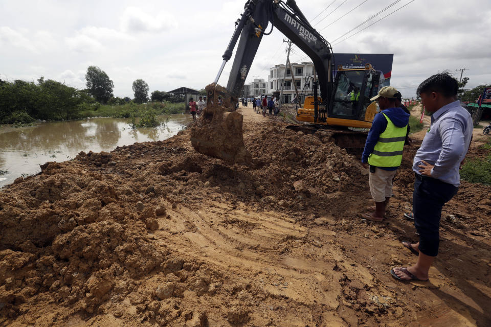 Local authorities try to repair damages near the Stung Prek Tnaot dam after the area was flooded following recent rains on the outskirts of Phnom Penh, Cambodia, Wednesday, Oct. 14, 2020. A Cambodian disaster official said Wednesday that more than 10,000 people have been evacuated to safety places after a tropical storm hit the country, causing the flash flood. (AP Photo/Heng Sinith)