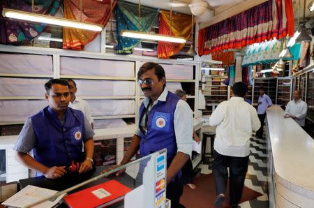 Municipal officers, who are part of a plastic eradication squad, speak to a business owner as others check for plastic bags inside a showroom at a market in Mumbai, India, June 27, 2018. REUTERS/Danish Siddiqui