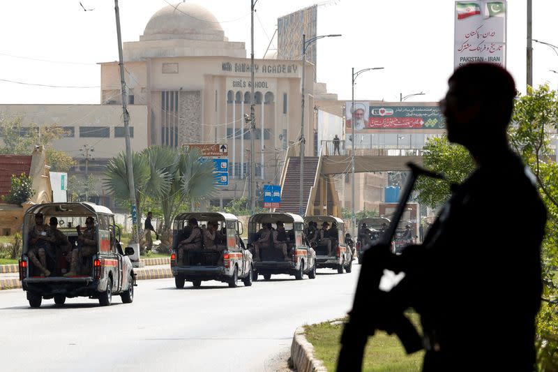 Police officer is silhouetted as he stands guard while paramilitary forces patrol for security measures, followig the visit of the Iranian President Ebrahim Raisi, in Karachi