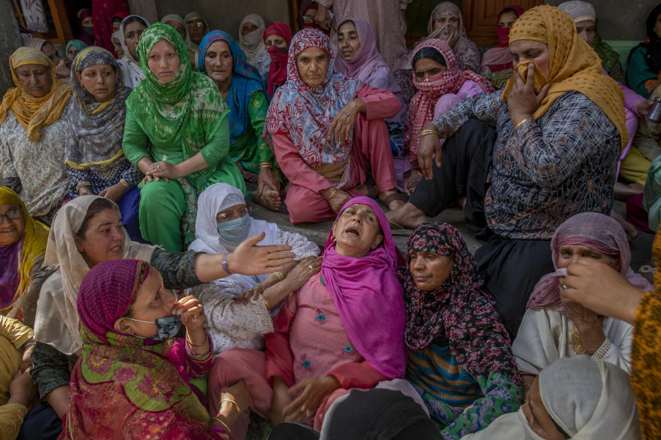 Women gather around the wailing mother, center in pink, of policeman Waseem Ahmed, who was killed in a shootout, on the outskirts of Srinagar Indian controlled Kashmir, Sunday, June 13, 2021. Two civilians and two police officials were killed in an armed clash in Indian-controlled Kashmir on Saturday, police said, triggering anti-India protests who accused the police of targeting the civilians. (AP Photo/ Dar Yasin)