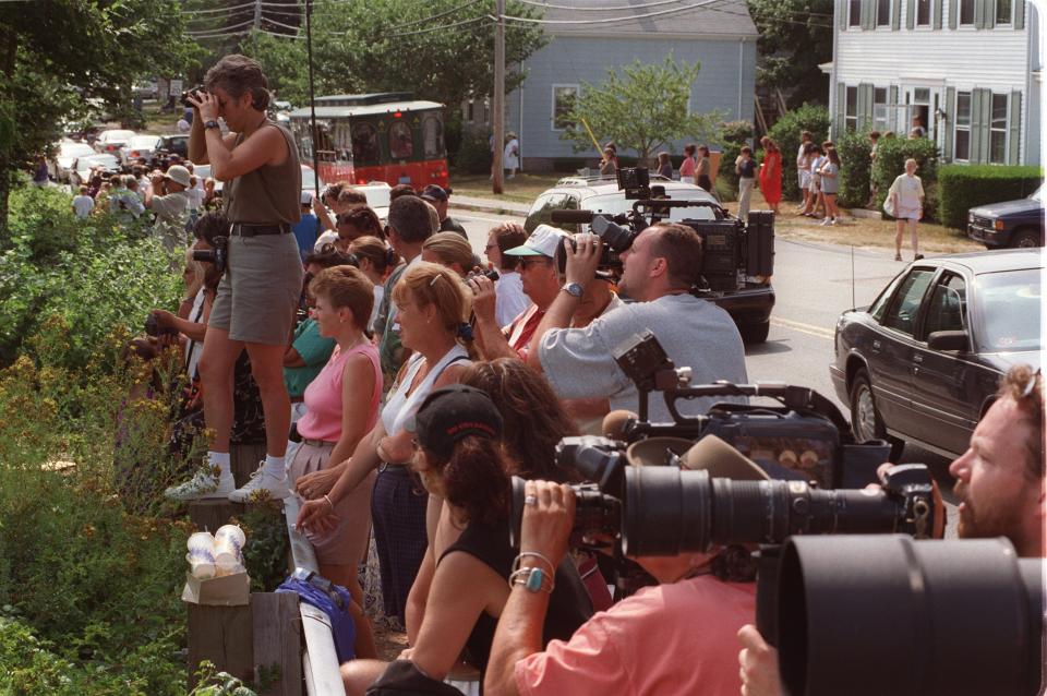 Members of the media and spectators crowd Main Street in Woods Hole to watch the arrival of the Kennedy family after a burial at sea for John F. Kennedy Jr, his wife Carolyn Bessette Kennedy, and her sister Lauren Bessette. The three died in a plane crash July 16, 1999, off Martha's Vineyard.