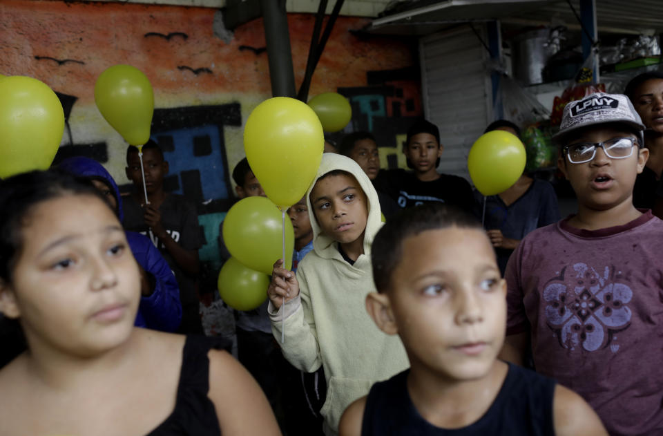 Youths attend a protest and gathering in memory of the late 8-year-old Ágatha Sales Félix, whose photo of her clutching a yellow balloon is circulating online, as residents demand an end to the violence in the Alemao complex slum of Rio de Janeiro, Brazil, Sunday, Sept. 22, 2019. Félix was hit by a stray bullet Friday amid what police said was shootout with suspected criminals. However, residents say there was no shootout, and blame police. (AP Photo/Silvia Izquierdo)