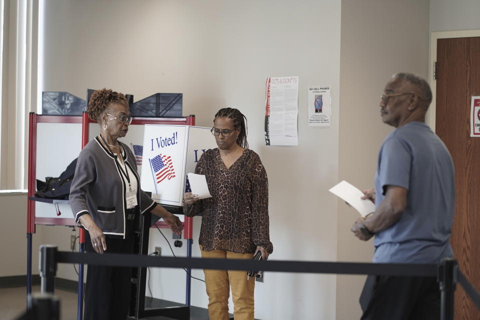 Deena Clarkson, 63, center, walks her ballot to the scanner, while Joseph Clarkson Sr., 72, goes to a booth to work on his ballot during the South Carolina Democratic primary at a Richland County early voting site in Columbia, S.C., Friday, Jan. 26, 2024. Both of them said they voted for President Joe Biden. (AP Photo/Serkan Gurbuz)