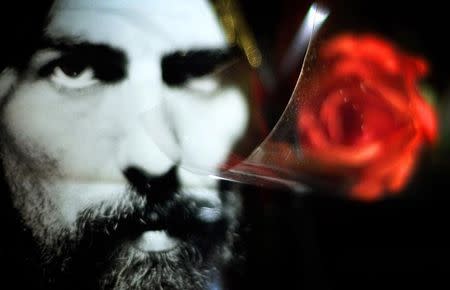 A red rose is placed next to a portrait of former Beatle George Harrison on the gates of the Abbey Road Studios in London November 30, 2001. REUTERS/Kieran Doherty