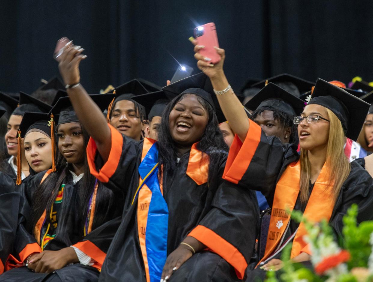 Graduates hold their phones and sway as Jay Li Mejia Ortiz sings during the North High School commencement Monday at the DCU Center.