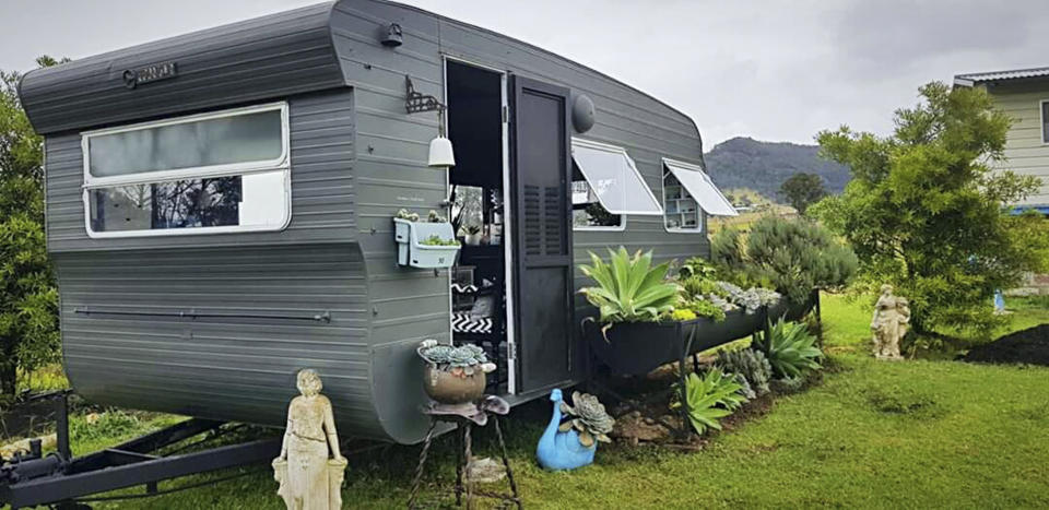 Caravan after renovation DIY surrounded by plants, painted grey, full working craft room