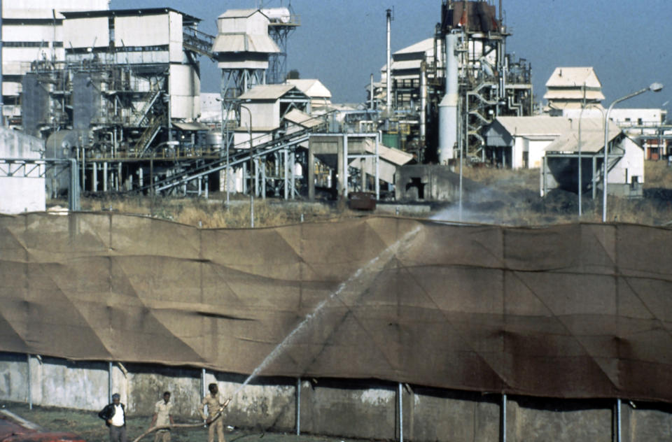 FILE - Firemen use a hose to wet canvas screens at factory boundaries to prevent the spread of dangerous fumes at the Union Carbide plant in Bhopal, India, December, 1984. On Dec. 3, 1984, the pesticide plant run by Union Carbide leaked about 40 tons of deadly methyl isocyanate gas into the air, killing an estimated 15,000 people and affecting at least 500,000 more. Michigan-based Dow Chemical Co. took over Union Carbide in 2001. (AP Photo/Peter Kemp, File)