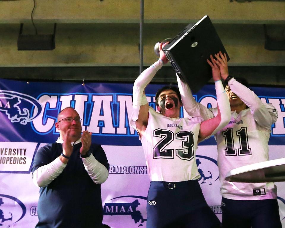 Rockland’s Lucas Leander and PJ Celestino lift the newly earned trophy following their 23-13 win over Abington in the Division 6 state title game at Gillette Stadium on Friday, Dec. 3, 2021.