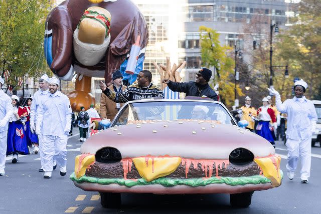<p>Gotham/GC Images</p> Kenan Thompson and Kel Mitchell ride along the parade route, with the semi-deflated Uncle Dan ballon just behind them.