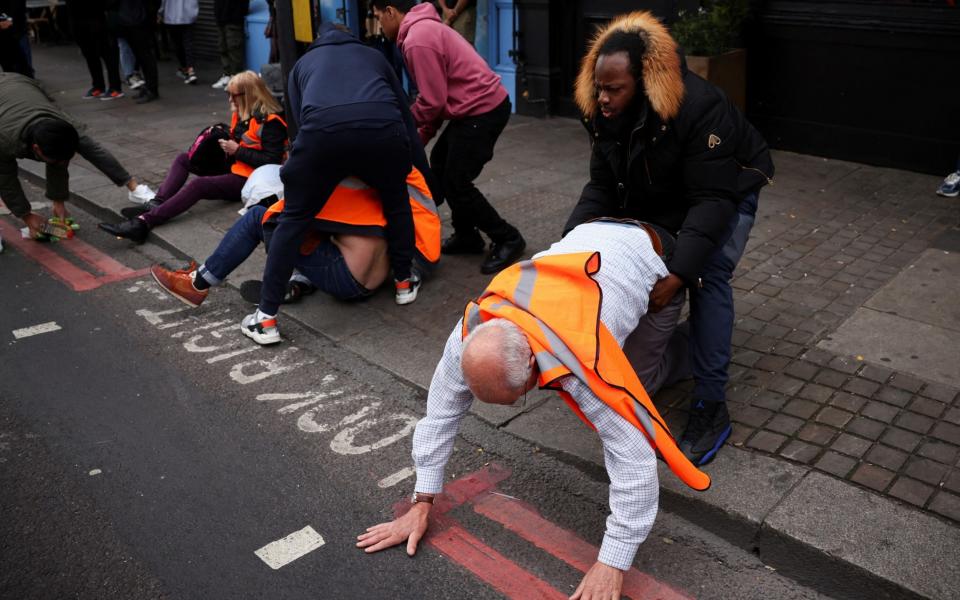 Member of the public drag activists who are blocking the road during a "Just Stop Oil" protest, in London, Britain,
