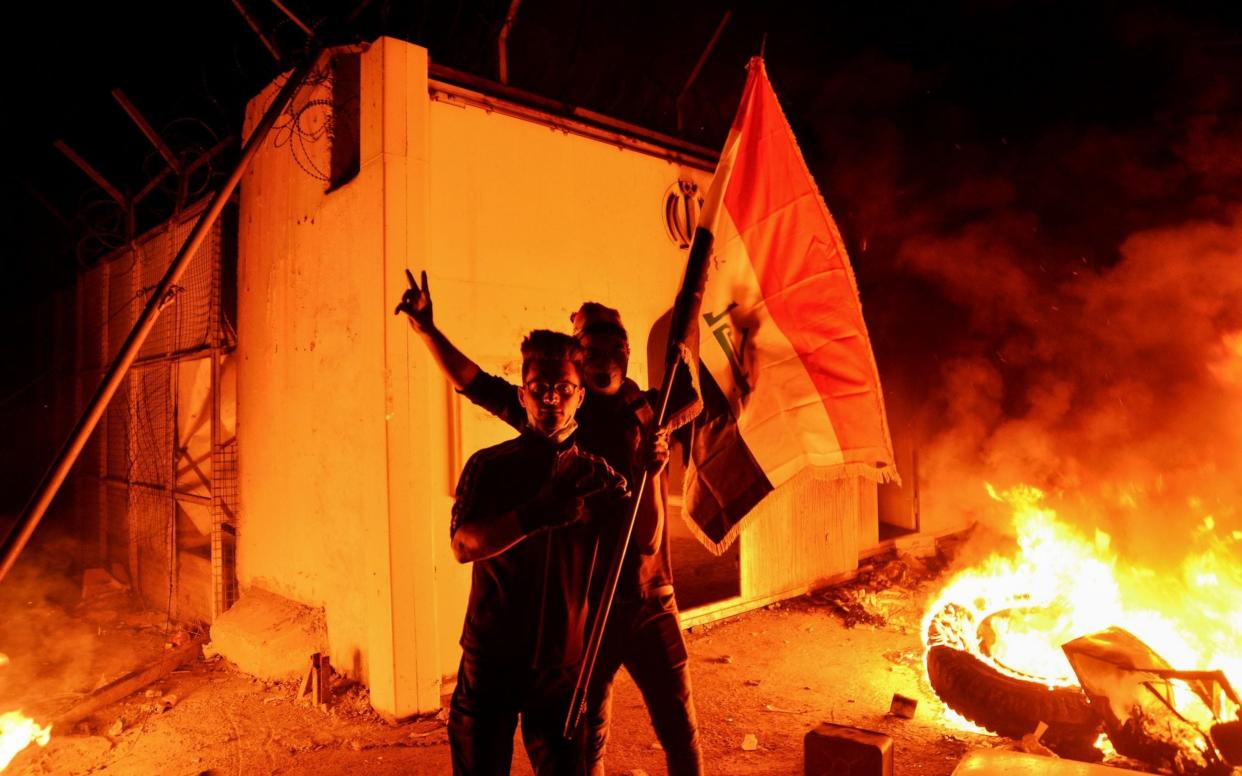 Iraqi demonstrators wave the Iraqi flag as flames consume Iran's consulate in the southern Iraqi Shia holy city of Najaf on Wednesday night - AFP