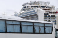 Bus carrying the passengers from the quarantined Diamond Princess cruise ship leave a port in Yokohama, near Tokyo, Thursday, Feb. 20, 2020. Passengers tested negative for COVID-19 started disembarking since Wednesday. (AP Photo/Eugene Hoshiko)