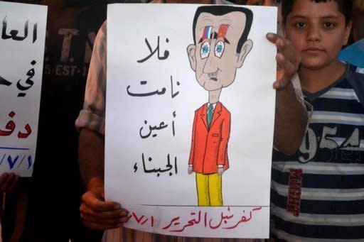 A handout image released by the Syrian opposition's Shaam News Network on July 2, shows a Syrian protester holding a poster depicting Bashar al-Assad with the Arabic writing "May the eyes of cowards never rest" during an anti-regime demonstration in Kfar Nubul. AFP cannot independently verify this image