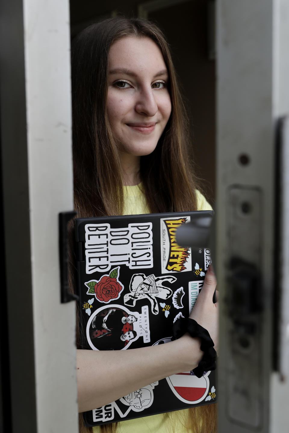 In this April 28, 2020 photo, Zofia Oles holds her laptop in Willowbrook, Ill. Oles is a senior at Hinsdale South high school and submitted her art work to the the Illinois State Museum, which is documenting what daily life is like for Illinois families during the coronavirus pandemic. (AP Photo/Nam Y. Huh)