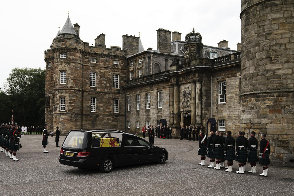The hearse carrying the coffin of Queen Elizabeth II, draped with the Royal Standard of Scotland, completes its journey from Balmoral to the Palace of Holyroodhouse, where it will lie in rest for a day, in Edinburgh, Sunday, Sept. 11, 2022. Queen Elizabeth II, Britain's longest-reigning monarch and a rock of stability across much of a turbulent century, died Thursday Sept. 8, 2022, after 70 years on the throne. She was 96. (Aaron Chown/Pool Photo via AP)