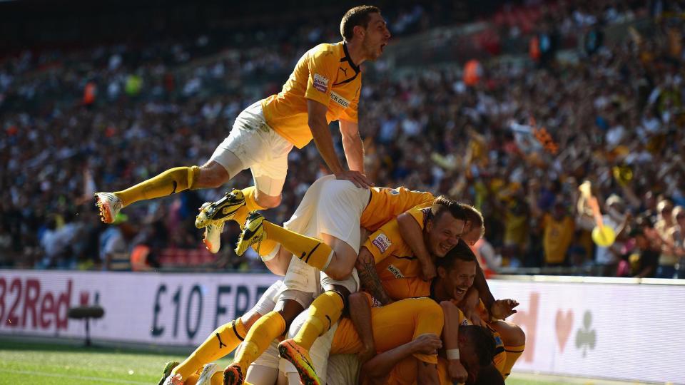 Cambridge United players pile on top of each other in celebration
