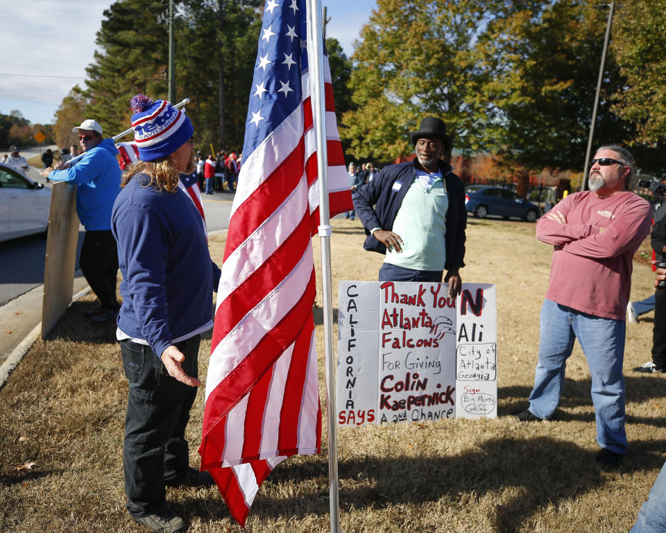 Protesters and supporters wait at the gate to the Atlanta Falcons' training facility where free agent quarterback Colin Kaepernick was set to workout for NFL football scouts, Saturday, Nov. 16, 2019, in Flowery Branch, Ga. The workout was moved to a high school in Riverdale, Ga. (AP Photo/Todd Kirkland)