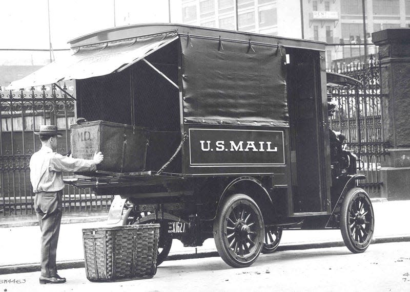 A letter carrier loading mail into an Autocar truck in Pennsylvania circa 1914.