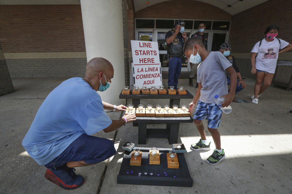 Matt Mouton and his son Mathew "MJ", 6, put finishing touches on a memorial he built in honor of U.S. Army Specialist Vanessa Guillen at Cesar Chavez High School Friday, Aug. 14, 2020, in Houston. Guillen, who was last seen on April 22, was laid to rest nearly four months after she is said to have been killed by a fellow soldier at Fort Hood, a U.S. Army base in Texas. (Steve Gonzales/Houston Chronicle via AP)