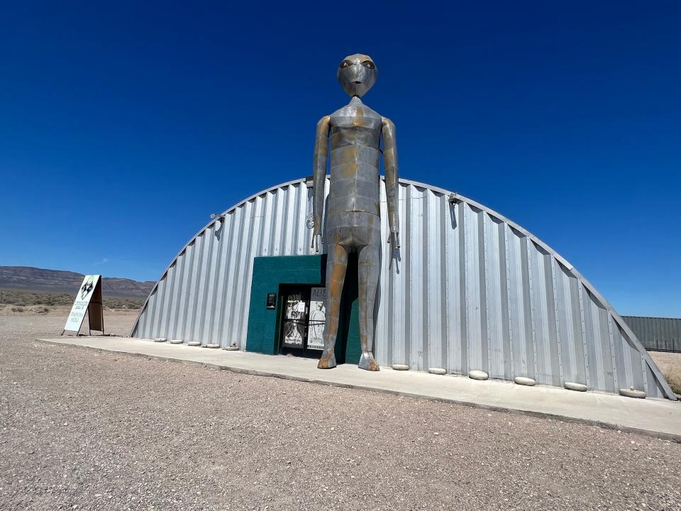 A giant metal alien statue that towers over a dome-shaped building.