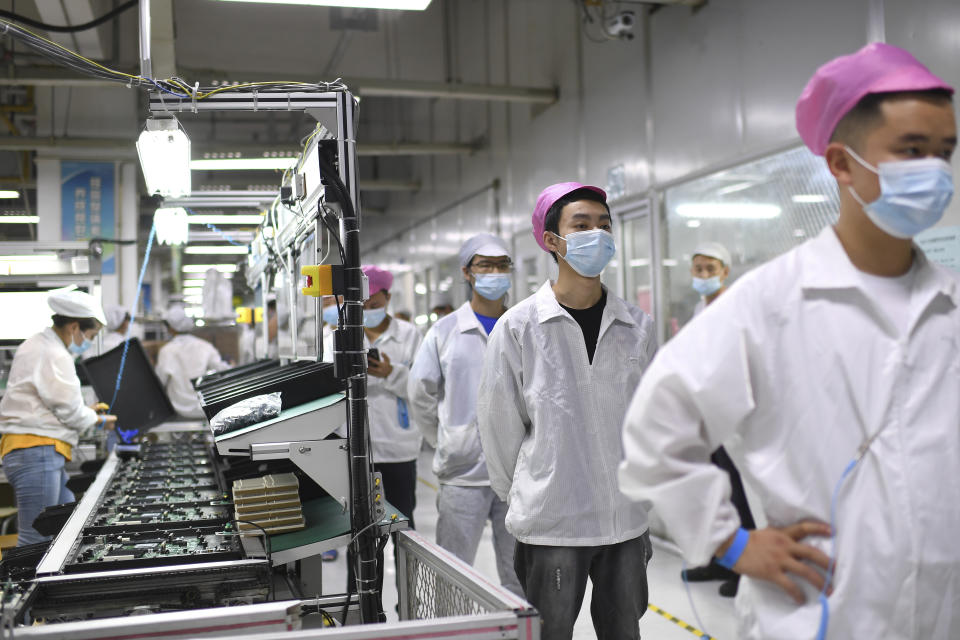 FILE - Workers line up to get tested for COVID-19 at the Foxconn factory in Wuhan in central China's Hubei province on Aug. 5, 2021. Foxconn, the company that assembles Apple Inc.’s iPhones, has announced it is easing COVID-19 restrictions at its largest factory, in Zhengzhou, central China, that led thousands of workers to quit and drastically slowed production. (Chinatopix via AP, File)