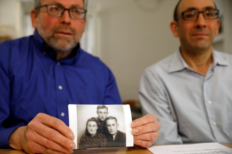 Brothers Eli and Saul Lieberman show a photograph of their late father Joseph (top), a survivor of the Nazi death camp Auschwitz, taken several years after the Holocaust, during an interview with Reuters in Jerusalem January 13, 2020. REUTERS/Ronen Zvulun