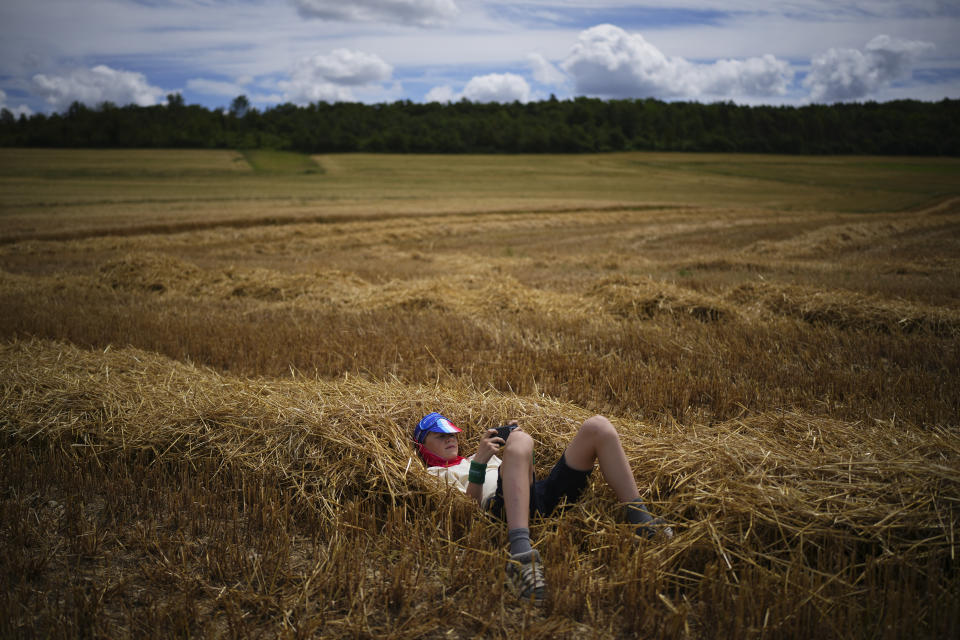 A cycling fan uses his mobile phone while waiting for the riders to pass on a gravel section of the ninth stage of the Tour de France cycling race over 199 kilometers (123.7 miles) with start and finish in Troyes, France, Sunday, July 7, 2024. (AP Photo/Daniel Cole)