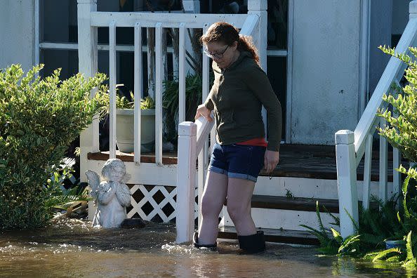 A woman walks down the stairs from her house as a creek overflows from flooding following Hurricane Ian on September 30, 2022 in Kissimmee, Florida. - Forecasters expect Hurricane Ian to cause life-threatening storm surges in the Carolinas on Friday after unleashing devastation in Florida, where it left a yet unknown number of dead in its wake. After weakening across Florida, Ian regained its Category 1 status in the Atlantic Ocean and was headed toward the Carolinas, the US National Hurricane Center said Friday. (Photo by Bryan R. Smith / AFP) (Photo by BRYAN R. SMITH/AFP via Getty Images)