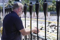 An attendee at a remembrance event at the site of the Champlain Towers South building collapse, takes a moment as he looks out at the area where the building once stood, Friday, June 24, 2022, in Surfside, Fla. Friday marks the anniversary of the oceanfront condo building collapse that killed 98 people in Surfside, Florida. The 12-story tower came down with a thunderous roar and left a giant pile of rubble in one of the deadliest collapses in U.S. history. (AP Photo/Wilfredo Lee)