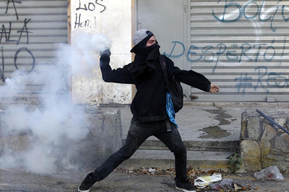 An anti-government protester throws a tear gas canister after it was fired by riot police during a protest against Nicolas Maduro's government in Caracas March 3, 2014. Jailed Venezuelan opposition leader Leopoldo Lopez urged sympathizers on Monday to maintain street protests against President Nicolas Maduro as the country's foreign minister prepared to meet the United Nations Secretary General. REUTERS/Carlos Garcia Rawlins